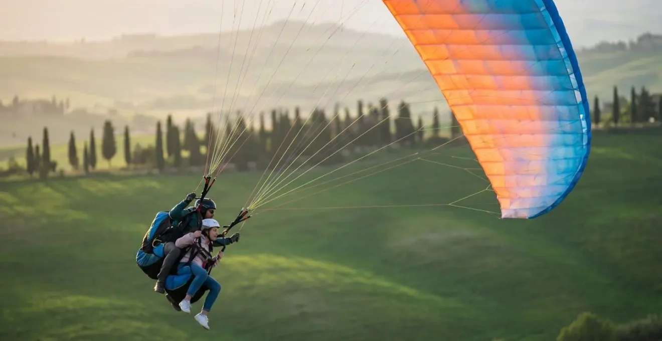 Parapendio biposto sopra colline verdi italiane con istruttore e allievo