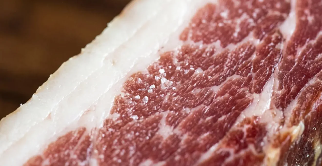 Dettaglio macro di prosciutto stagionato con strato di grasso uniforme